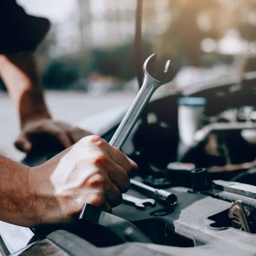 Car mechanic is holding a wrench ready to check the engine and maintenance.