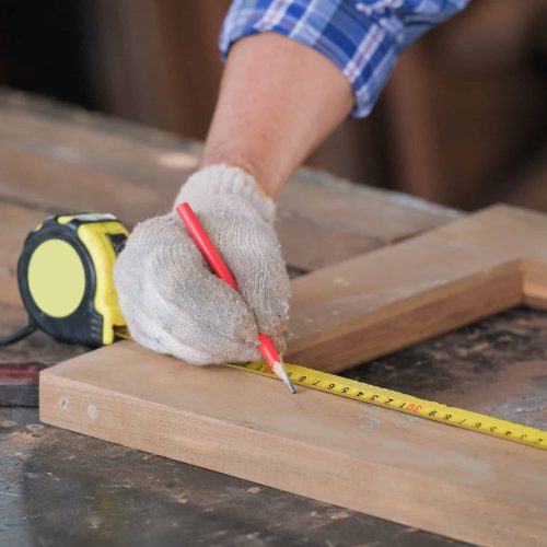 Carpenter men work on the measurements of wood in a carpentry shop.